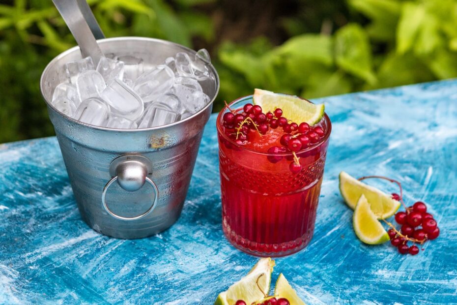 ice cream in clear drinking glass with strawberry and white cream on blue table